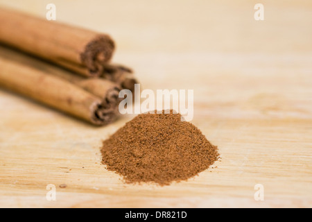 Bastoncini di cannella e la cannella in polvere su una tavola di legno. Foto Stock