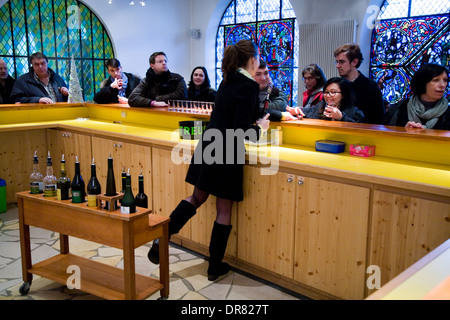 I turisti essendo servito di campioni di liquore Chartreuse al tourist negozio della fabbrica della distilleria della Chartreuse monaci. La Francia. Foto Stock