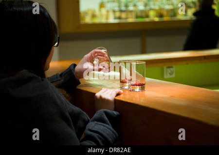 I turisti essendo servito di campioni di liquore Chartreuse al tourist negozio della fabbrica della distilleria della Chartreuse monaci. La Francia. Foto Stock