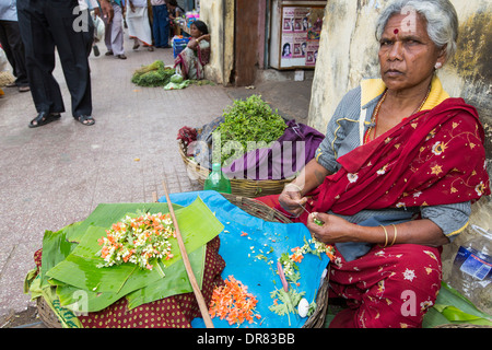 Una donna che fa floral decorazioni capelli ad una strada del mercato di Mysore, India. Foto Stock