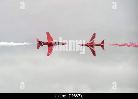 Due BAE Hawk Mk 1 Formatori del British RAFAerobatic team Display, le frecce rosse eseguire la loro testa a testa croce sopra Foto Stock