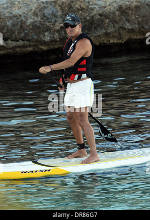 Il cantante Bruce Springsteen facendo paddlesurf su una spiaggia in vacanza a Maiorca nel 2013. Foto Stock