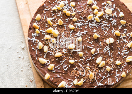 Un haupia decadente e crema al cioccolato torta guarnita con radere noce di cocco, noci di macadamia e scaglie di cioccolato Foto Stock