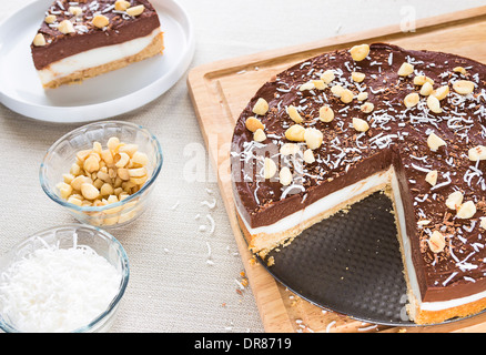 Un haupia decadente e crema al cioccolato torta guarnita con radere noce di cocco, noci di macadamia e scaglie di cioccolato Foto Stock
