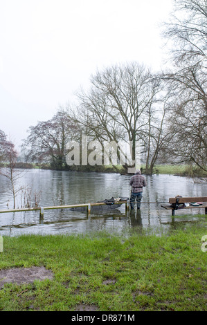 Pescatore in piedi di inondazione sul fiume Avon a Harnham Mill Salisbury WILTSHIRE REGNO UNITO Foto Stock