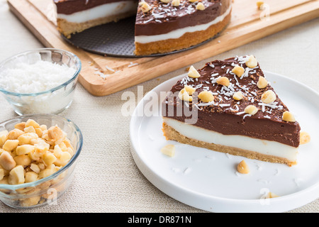 Un haupia decadente e crema al cioccolato torta guarnita con radere noce di cocco, noci di macadamia e scaglie di cioccolato Foto Stock