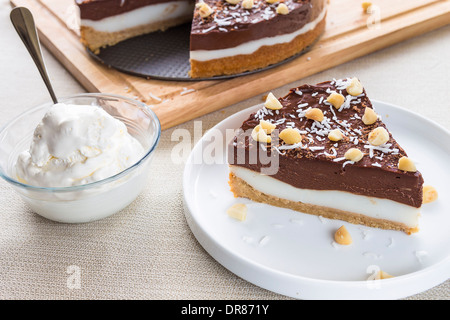 Haupia decadente e crema al cioccolato torta guarnita con radere noce di cocco, noci di macadamia e scaglie di cioccolato con panna montata Foto Stock