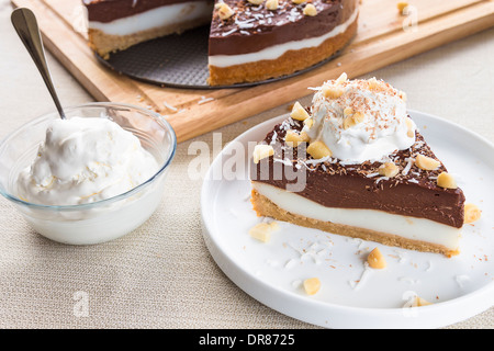 Haupia decadente e crema al cioccolato torta guarnita con radere noce di cocco, noci di macadamia e scaglie di cioccolato con panna montata Foto Stock