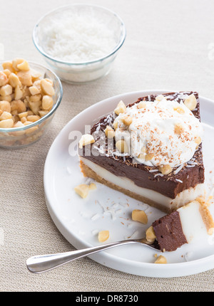 Haupia decadente e crema al cioccolato torta guarnita con radere noce di cocco, noci di macadamia e scaglie di cioccolato con panna montata Foto Stock