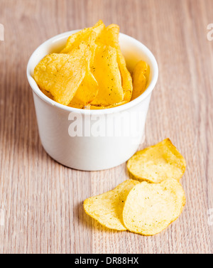 Potato Chips in ciotola bianco su sfondo di legno Foto Stock