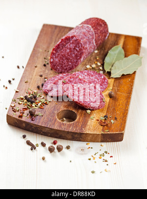 Fette di salame con pepe su un tavolo di legno Foto Stock