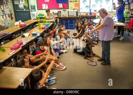 Un prevalentemente ispanica scuola elementare classe in San Bernardino, CA, ottiene una lezione nella cura del cane dal proprietario di un rottweiler. Foto Stock