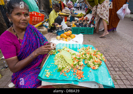 Una donna che fa floral decorazioni capelli ad una strada del mercato di Mysore, India. Foto Stock