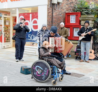 Bambino in sedia a rotelle essendo intrattenuti da musicisti di strada Foto Stock