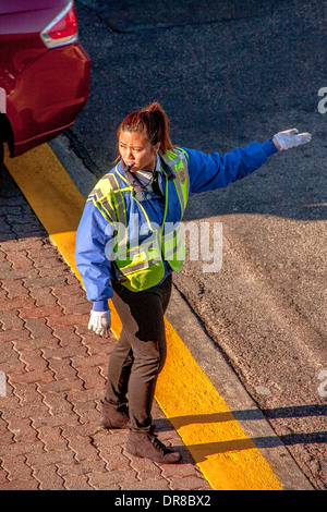 Un americano asiatico police officer dirige il traffico sul campus della University of California a Irvine. Nota luminosa luce del mattino e visibilità abbigliamento di sicurezza. Foto Stock