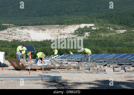 Lavoratori tra i pannelli solari vicino al completamento installazione in Adams, Massachusetts. Lavoro fossa di calce in background. Foto Stock