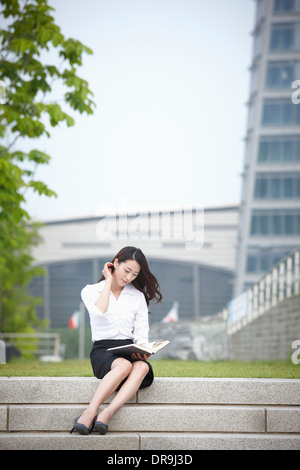 Un business donna seduta al di fuori e funzionante Foto Stock