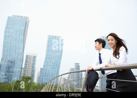 Un uomo di affari e una donna d'affari appoggiato su di una recinzione Foto Stock