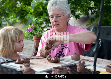 Insegnante dimostrando l'arte della ceramica di modellazione di argilla studente età 3 nel cortile esterno di classe. St Paul Minnesota MN USA Foto Stock