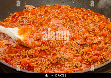 Il ragù alla bolognese riscaldamento in padella con il cucchiaio di legno Foto Stock