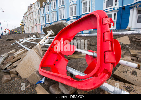 Dopo una settimana di alta marea, mareggiate e tempesta vigore venti, il lungomare di Aberystwyth in Galles è stato devastato, con milioni di £ 's di danni. Le onde che si infrangono punzonato un grande foro nella parete del mare ed è crollato Aberystwyth iconici, lungomare vittoriano rifugio, che ha resistito per oltre 100 anni. Questa foto è stata scattata mercoledì 8 gennaio, 2014, il giorno in cui il Consiglio ha cominciato a cercare di cancellare le migliaia di tonnellate di macerie spiaggia fuori di fronte al mare su strada. Foto Stock