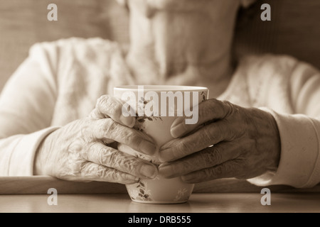Signora anziana negli anni novanta la sua azienda tazza di tè Foto Stock