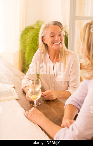 Le donne anziane di bere il vino bianco al tavolo da pranzo Foto Stock