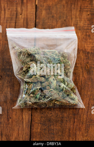 Grande busta di plastica delle malerbe o marijuana su sfondo di legno Foto Stock