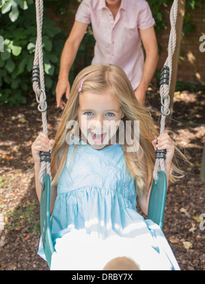 Padre spingendo la figlia a swing Foto Stock