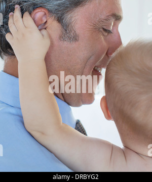 Close up baby grabbing padre l orecchio Foto Stock