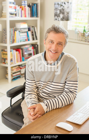 Uomo sorridente alla scrivania del computer Foto Stock
