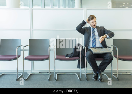 Imprenditore controllo orologio da polso in area di attesa Foto Stock