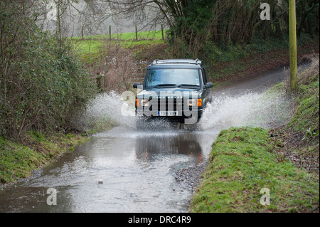 Land Rover Discovery 4x4 di guida attraverso le acque di esondazione su un vicolo del paese, Hampshire, Regno Unito Foto Stock