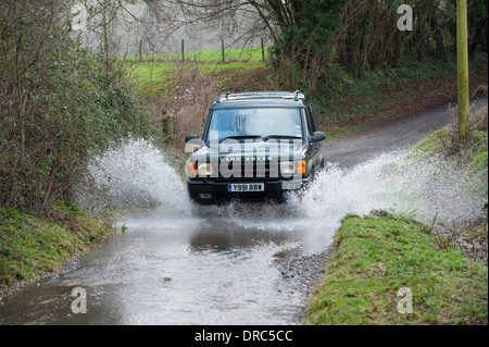 Land Rover Discovery 4x4 di guida attraverso le acque di esondazione su un vicolo del paese, Hampshire, Regno Unito Foto Stock