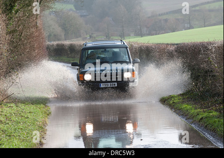 Land Rover Discovery 4x4 di guida attraverso le acque di esondazione su un vicolo del paese, Hampshire, Regno Unito Foto Stock