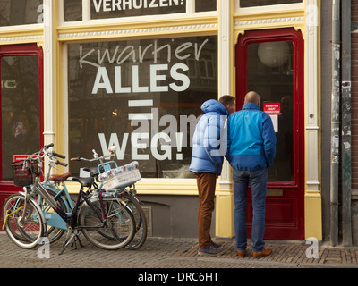 Due uomini la lettura di un segno su un negozio che è scomparso nel centro della città di Utrecht Foto Stock