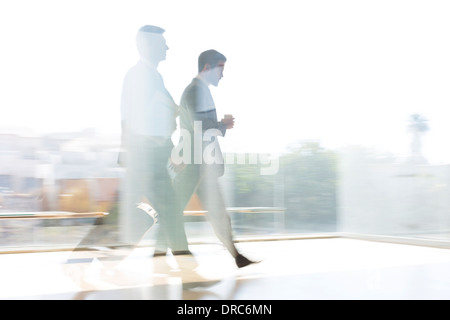 Imprenditori a piedi nella soleggiata corridoio airport Foto Stock