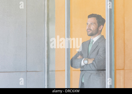 Imprenditore in piedi alla finestra di ufficio Foto Stock