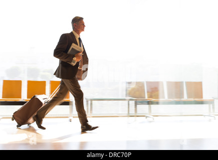 Imprenditore in esecuzione con la valigia nel corridoio di airport Foto Stock