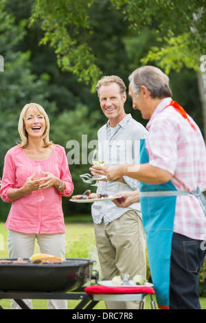 Famiglia permanente al barbecue nel cortile posteriore Foto Stock