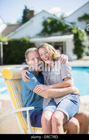 Giovane seduto in poltrona a bordo piscina Foto Stock