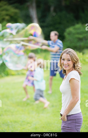 La famiglia gioca con bolle nel cortile posteriore Foto Stock