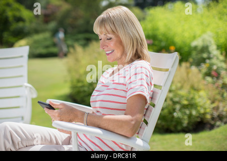 Donna che utilizza il cellulare in giardino Foto Stock