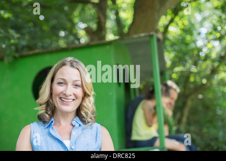 Donna sorridente con treehouse in background Foto Stock