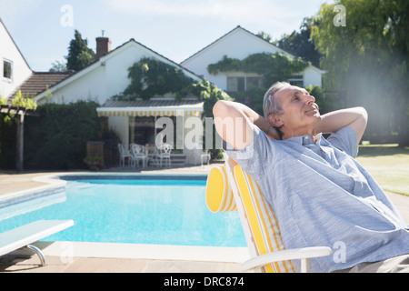 L'uomo rilassante in sedia a sdraio a bordo piscina Foto Stock