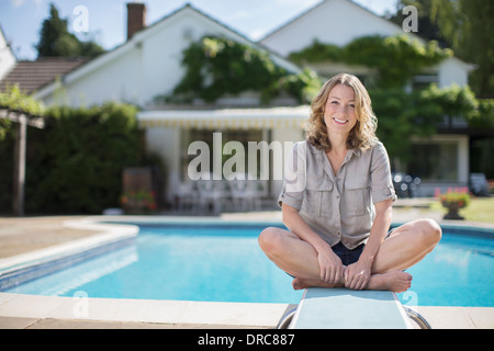 Donna seduta sulla scheda di immersioni presso la piscina Foto Stock