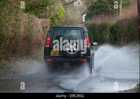 Land Rover Discovery 4x4 di guida attraverso le acque di esondazione su un vicolo del paese, Hampshire, Regno Unito Foto Stock