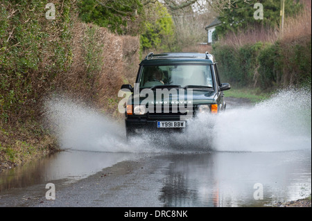 Land Rover Discovery 4x4 di guida attraverso le acque di esondazione su un vicolo del paese, Hampshire, Regno Unito Foto Stock