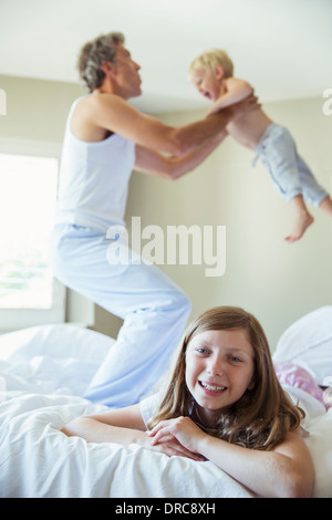 Padre e figli giocare sul letto Foto Stock