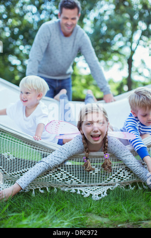 Padre spingendo i bambini in amaca all'aperto Foto Stock